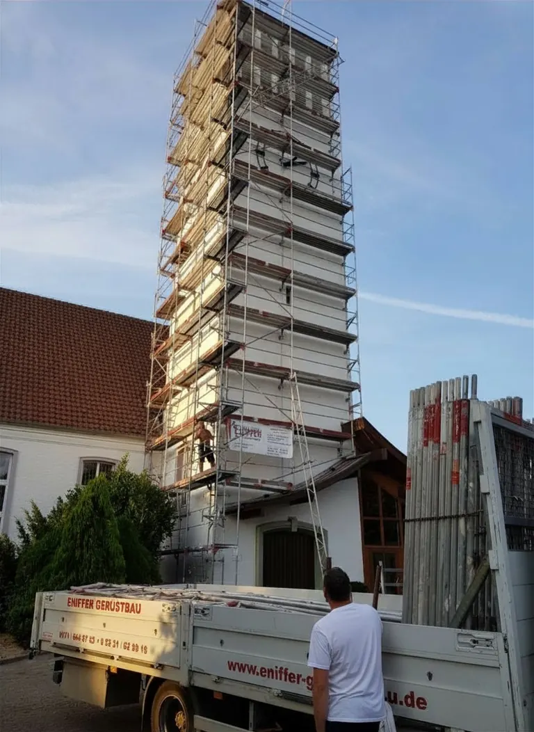 Gerüstbauer in roter Schutzkleidung auf einem Gerüst